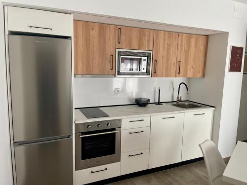 a kitchen with white cabinets and a stainless steel refrigerator at Apartamentos Palma del Río CAROLA in Linares