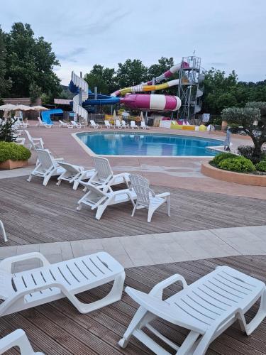 une piscine avec des chaises longues blanches et un parc aquatique dans l'établissement mobil-home 6 personnes chez maylia, à Cadenet
