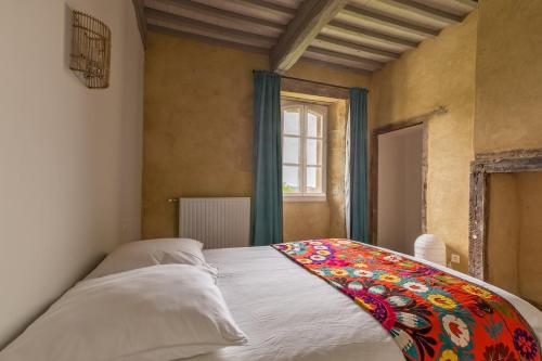 - une chambre avec un lit et une couverture colorée dans l'établissement Gîte Presbytère de Puységur 4*, à Puységur