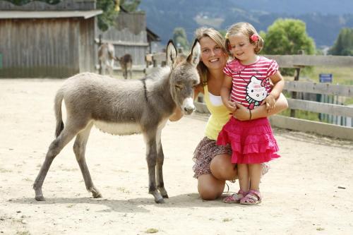 a woman and a little girl standing next to a donkey at Hotel Malteinerhof in Malta