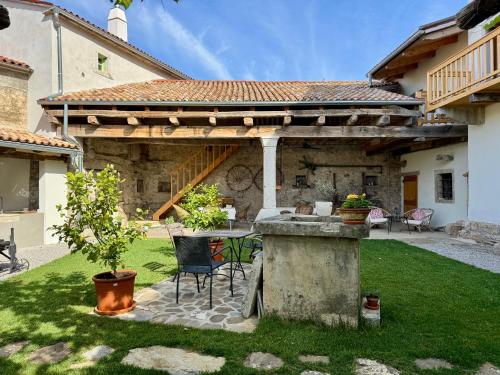 a patio with a table and chairs in a yard at Vila Kobdilj 1835 - Unique Stay in Karst Stone Villa in Štanjel