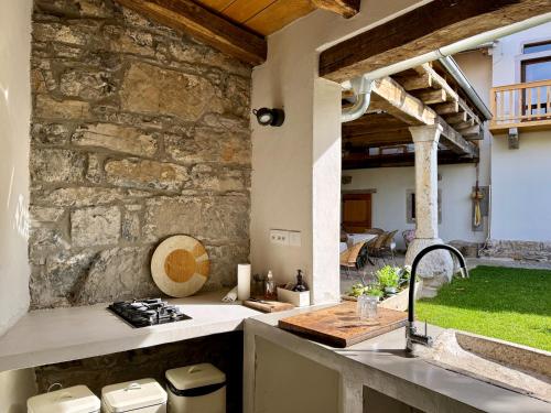 an outdoor kitchen with a stone wall and a sink at Vila Kobdilj 1835 - Unique Stay in Karst Stone Villa in Štanjel