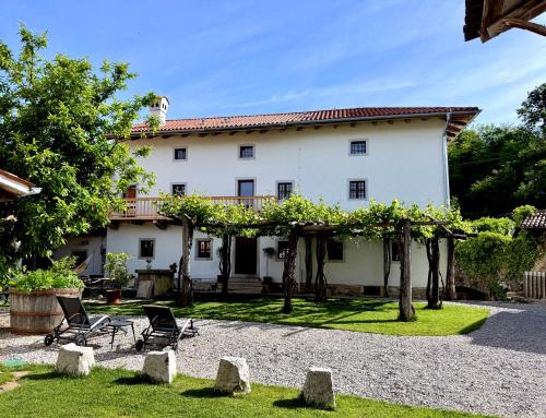 a white house with chairs and trees in front of it at Vila Kobdilj 1835 - Unique Stay in Karst Stone Villa in Štanjel