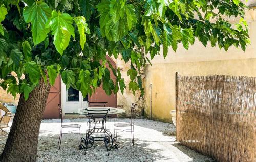 une table et des chaises sous un arbre dans une cour dans l'établissement Maison Piscine Proche Arles, à Tarascon
