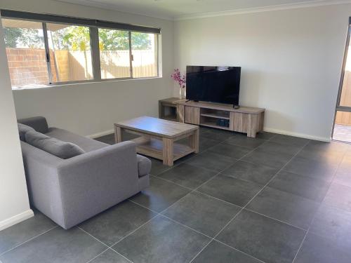 a living room with a couch and a flat screen tv at Canning Vale Family Accommodation in Perth
