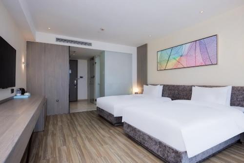 a hotel room with two beds and a tv at Mercure Shanghai Hongqiao South in Shanghai