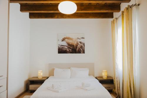 1 dormitorio con 1 cama con sábanas blancas y 2 velas en Casa Nicolae Luxury Suites, en Sibiu