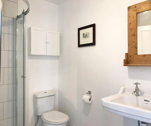 a white bathroom with a toilet and a sink at Woodland Lodge in London