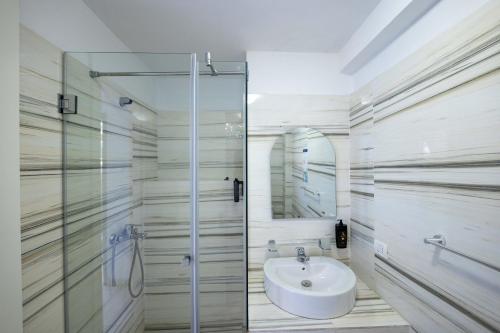 a bathroom with a sink and a glass shower at Stone Beach Residence - Adults Only Resort in Qeparo