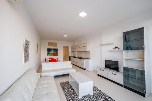 a living room with a white couch and a tv at Stone Beach Residence - Adults Only Resort in Qeparo