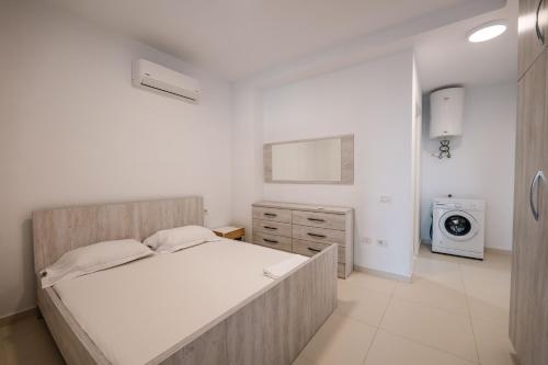 a white bedroom with a bed and a washing machine at Stone Beach Residence - Adults Only Resort in Qeparo
