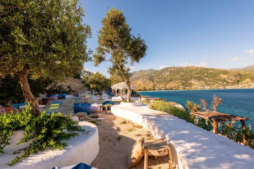 a view of the water and a beach with trees and chairs at Stone Beach Residence - Adults Only Resort in Qeparo