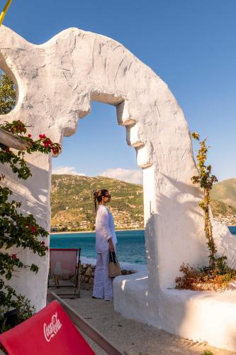 a woman standing in an archway in front of the water at Stone Beach Residence - Adults Only Resort in Qeparo
