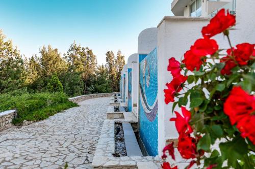 a street with red flowers next to a wall at Stone Beach Residence - Adults Only Resort in Qeparo
