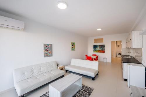a living room with white furniture and red chairs at Stone Beach Residence - Adults Only Resort in Qeparo