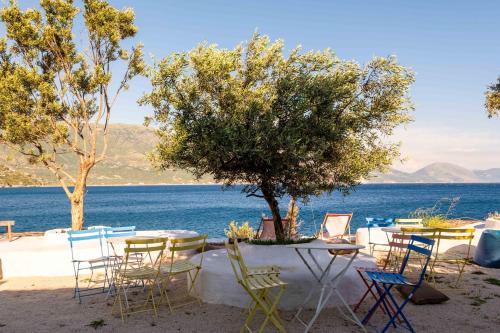 a table and chairs with a tree and water at Stone Beach Residence - Adults Only Resort in Qeparo
