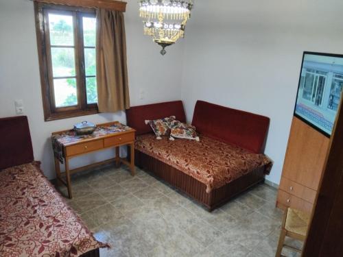a room with a couch and a table and a window at Μικρό Σπίτι στο Λιβάδι - Βικτώρια in Néa Sampsoús