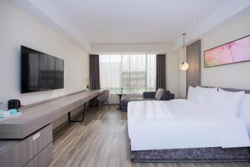 a hotel room with a large bed and a tv at Mercure Shanghai Hongqiao South in Shanghai