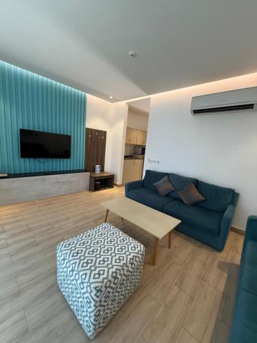 Una sala de estar con un sofá azul y una mesa. en LA Brisa Durrat Alarous شاليهات لابريزا درة العروس شاطئ البرادايس للعوائل فقط, en Durat Alarous