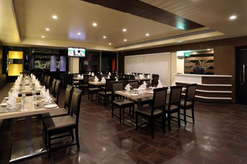 a dining room with tables and chairs and a television at Grand Kailash Hotel in Aurangabad
