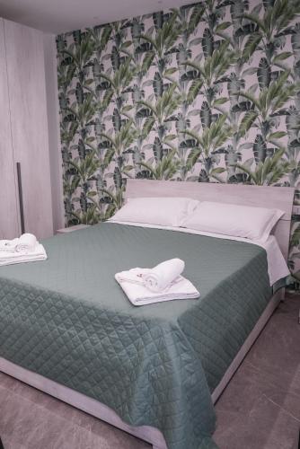 a bedroom with a green bed with towels on it at La Peonia B&B in Ragusa