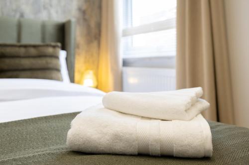 a pile of towels sitting on top of a bed at A spacious and modern 4Bedroom house in Borehamwood