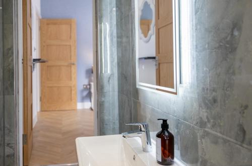 a bathroom with a sink with a soap bottle on it at A spacious and modern 4Bedroom house in Borehamwood