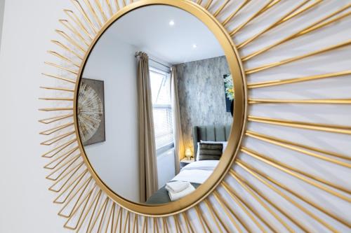 a gold mirror in a hotel room with a bedroom at A spacious and modern 4Bedroom house in Borehamwood