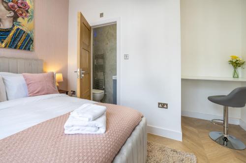 a bedroom with a bed with towels on it at A spacious and modern 4Bedroom house in Borehamwood