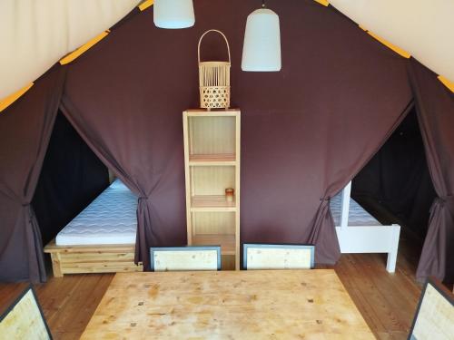 une chambre dans une tente avec un lit et des étagères dans l'établissement Tente Lodge pour 5 personnes en bordure de la rivière Allier au sein d'un petit camping, à Saint-Yorre