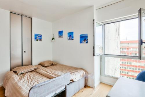 une chambre avec un lit et une grande fenêtre dans l'établissement Superbe studio à proximité de la Tour Eiffel, à Paris