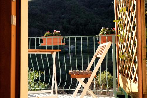 a wooden chair sitting on a balcony with flowers at Cà Du Praettu in Albisola Superiore