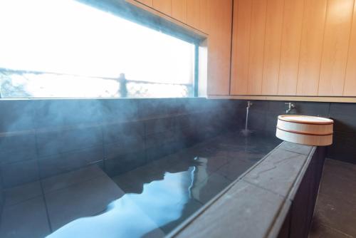 a bathroom with a tub with a toilet in it at 箱根御泊処-縁- 044h in Hakone