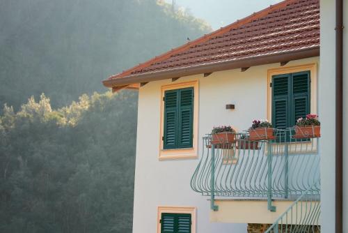 a building with green shutters and flowers on a balcony at Cà Du Praettu in Albisola Superiore