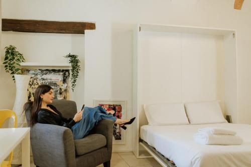 a woman sitting in a chair in a room with a bed at Yourbanflat Art Loft in Padova