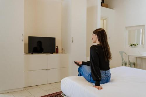 a woman sitting on a bed watching a tv at Yourbanflat Art Loft in Padova