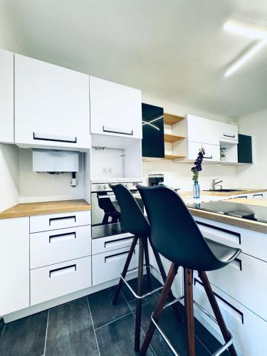 クロスターノイブルクにあるSpacious 2BR & 1LR Apt for 7P Peaceful Locationのキッチン(白いキャビネット、緑の椅子2脚付)