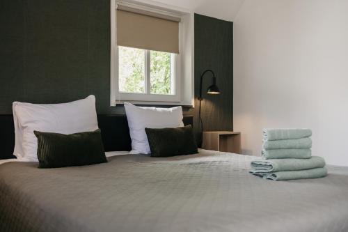 a bedroom with a large bed with green and white pillows at Gasterij de Heihorst in Someren