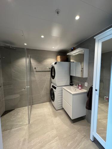 a bathroom with a shower and a sink and a refrigerator at Wonderful apartment in centrum in Tromsø