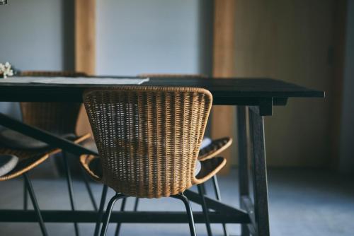 a wicker chair sitting at a black table at MUJI BASE kamogawa in Kamogawa