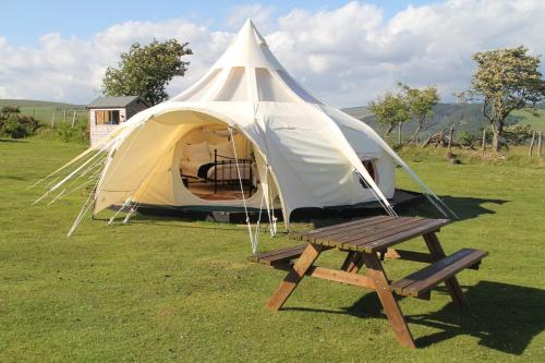 a tent with a bench and a picnic table in a field at Tal-y-fan farm 6m stargazer tent in Bridgend