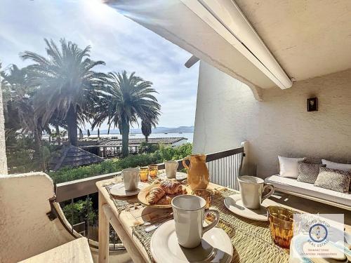 - une table avec de la nourriture et des boissons sur un balcon avec des palmiers dans l'établissement Saint-Tropez Élysée plage 9, à Saint-Tropez