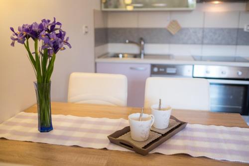 a table with two candles and a vase of purple flowers at Apartments Iva in Krk