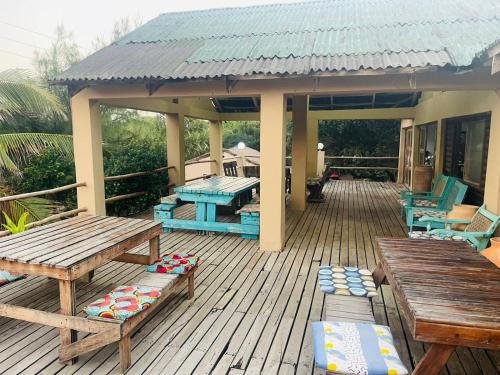 a wooden deck with picnic tables and a house at The View - Xai Xai Mozambique Xai Xai Beach Front 180 Degree Sea Views in Xai-Xai