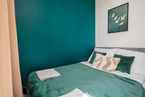 a bedroom with blue walls and a bed with pillows at Piotrkowska Sunset Apartment in Łódź