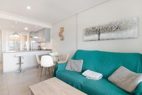 a living room with a green couch and a kitchen at Apartamento en Isla Canela in Ayamonte
