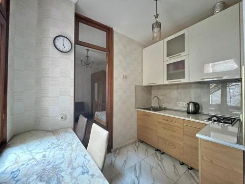 a kitchen with a sink and a clock on the wall at Apartment near Rustaveli theatre in Stantsiya Mukhiani