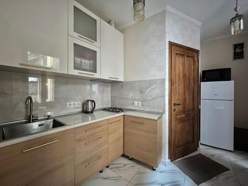 a kitchen with wooden cabinets and a white refrigerator at Apartment near Rustaveli theatre in Stantsiya Mukhiani