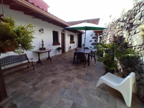 a patio with a table and chairs and an umbrella at Confortable Alojamiento para 2 con Piscina in Garachico