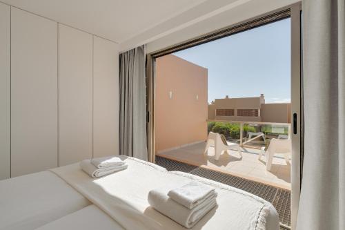 una camera da letto bianca con vista su un balcone di Salgados Premium Beach Villa by DA'Home ad Albufeira